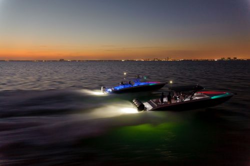 A landscape photo of the sea with two speed boats using a green LED light