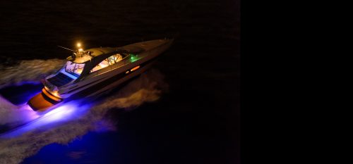 A boat travelling the sea when its dark using their purple LED Light